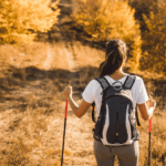 Woman nordic walking along forest footpath in autumn
