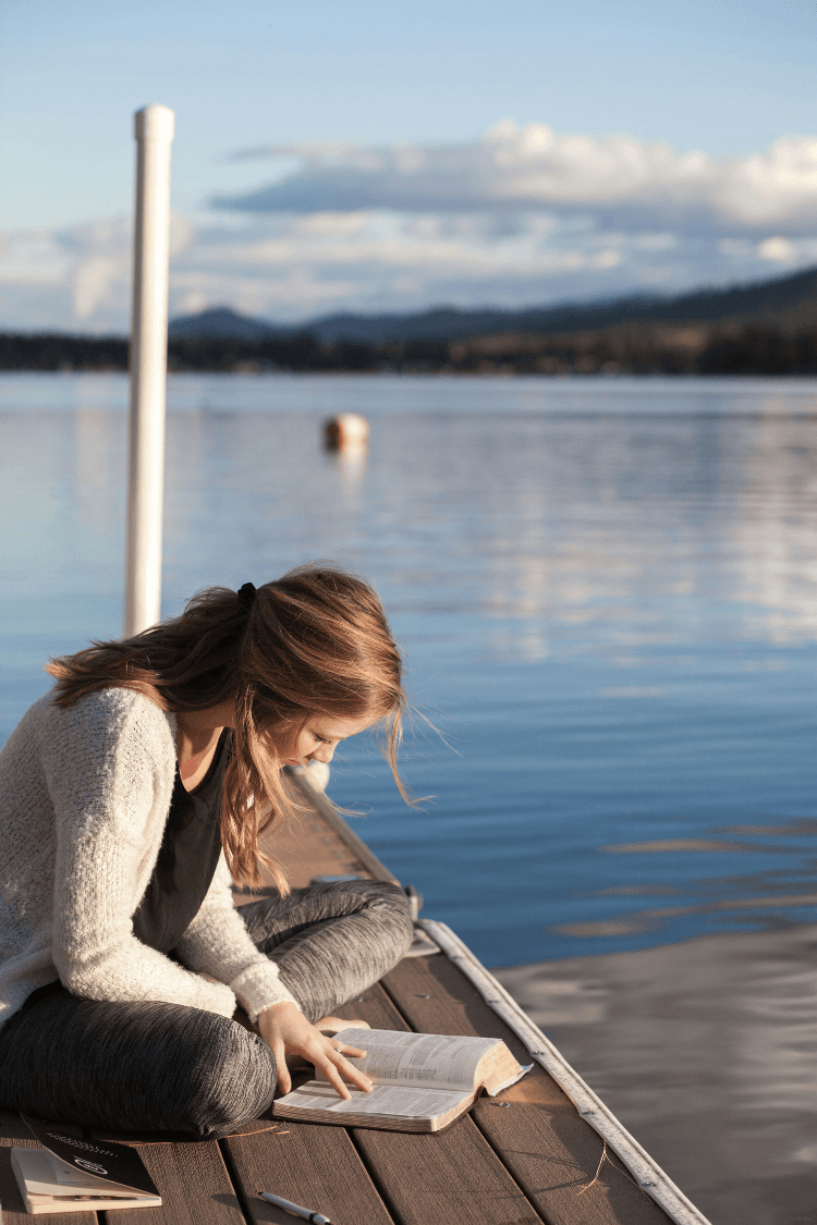 Woman reading a book by the water's edge