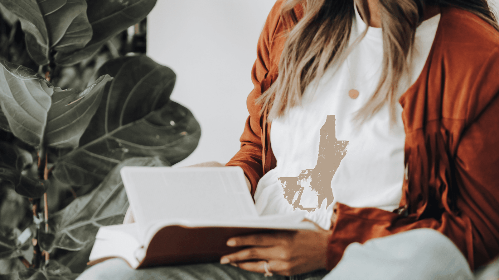 Woman wearing white t-shirt and orange cardigan reading a book