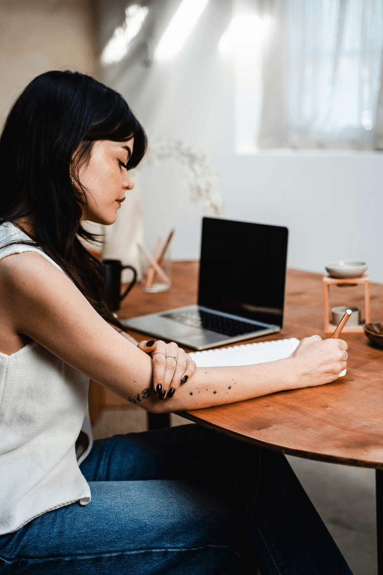 Woman sitting at table writing in journal