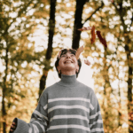 Woman smiling and looking up at autumn leaves