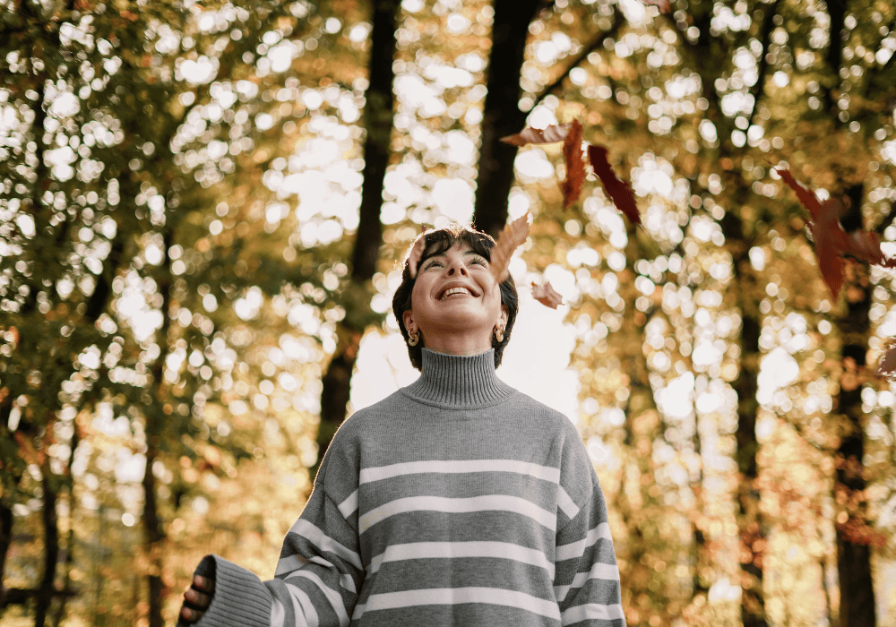 Woman smiling and looking up at autumn leaves