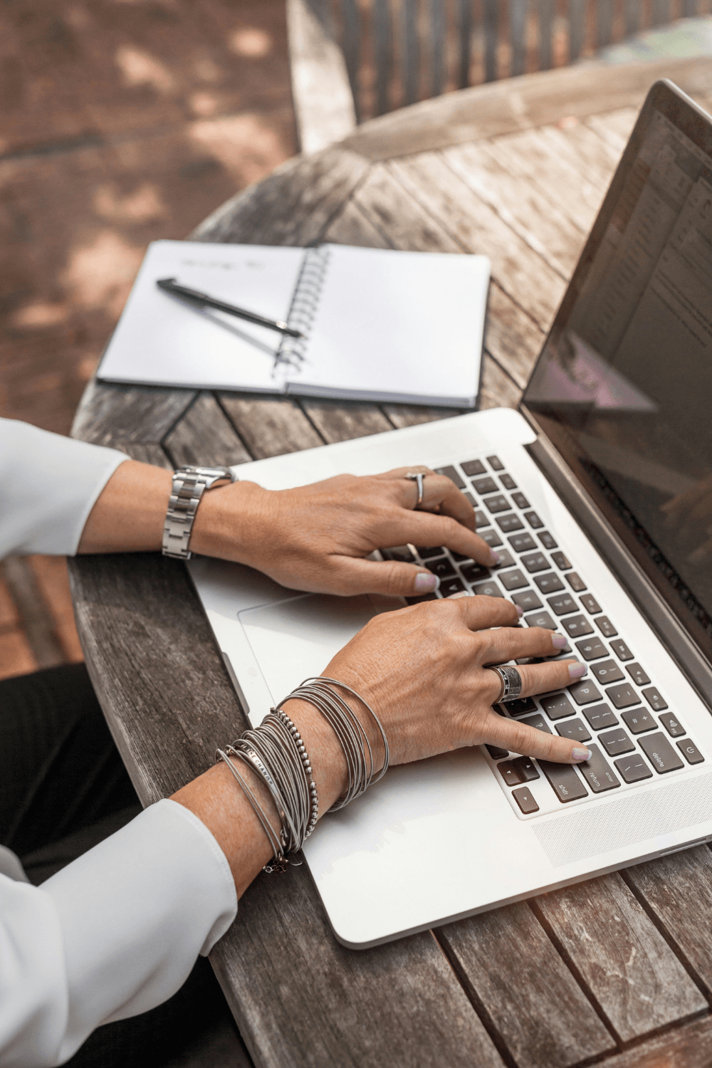 Woman typing on MacBook Pro sitting at rustic table