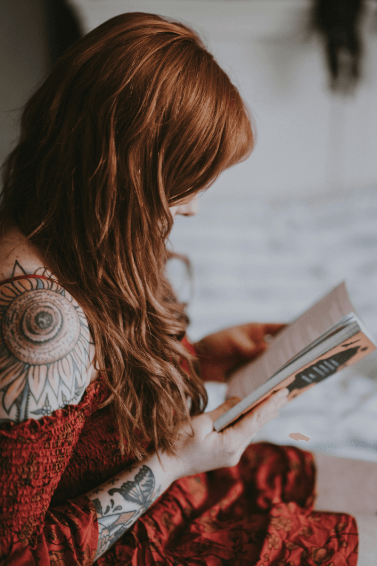 Woman with long auburn hair reading a book