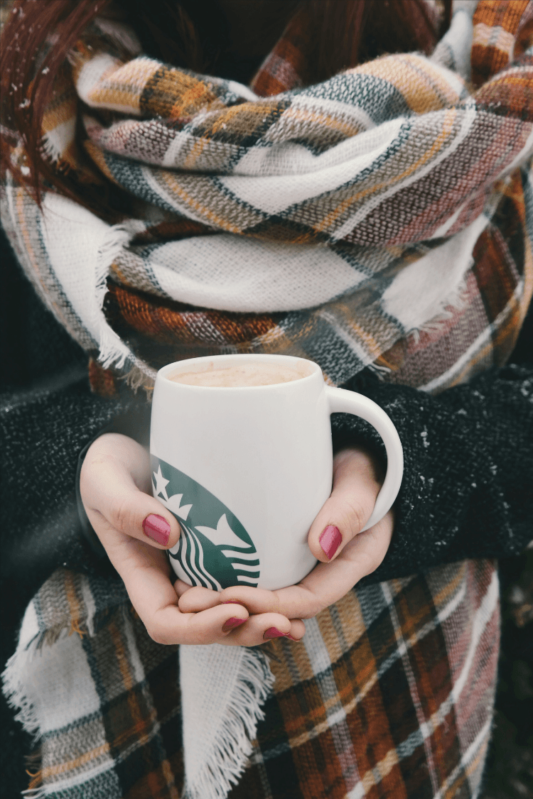 Woman wrapped in a cozy blanket with Starbucks mug