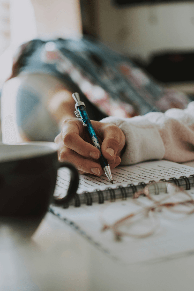 Woman writing in notebook with blue pen