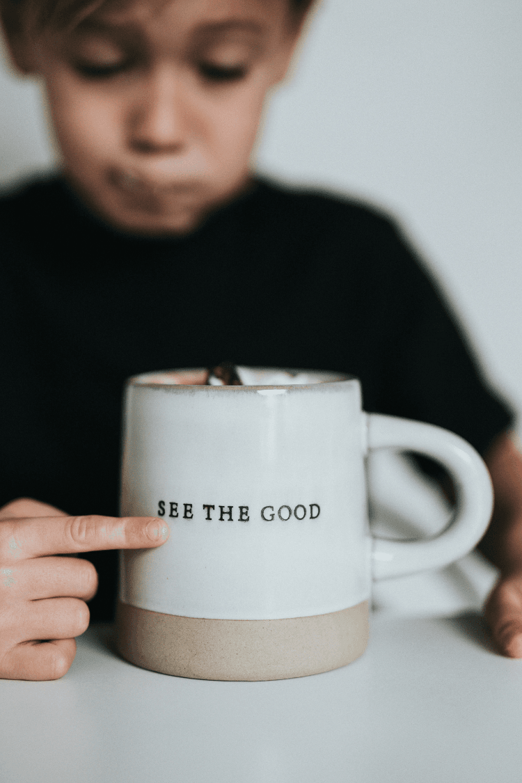 Young boy pointing at mug that says see the good