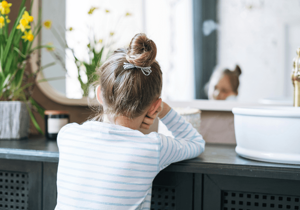 Young girl looking in bathroom mirror