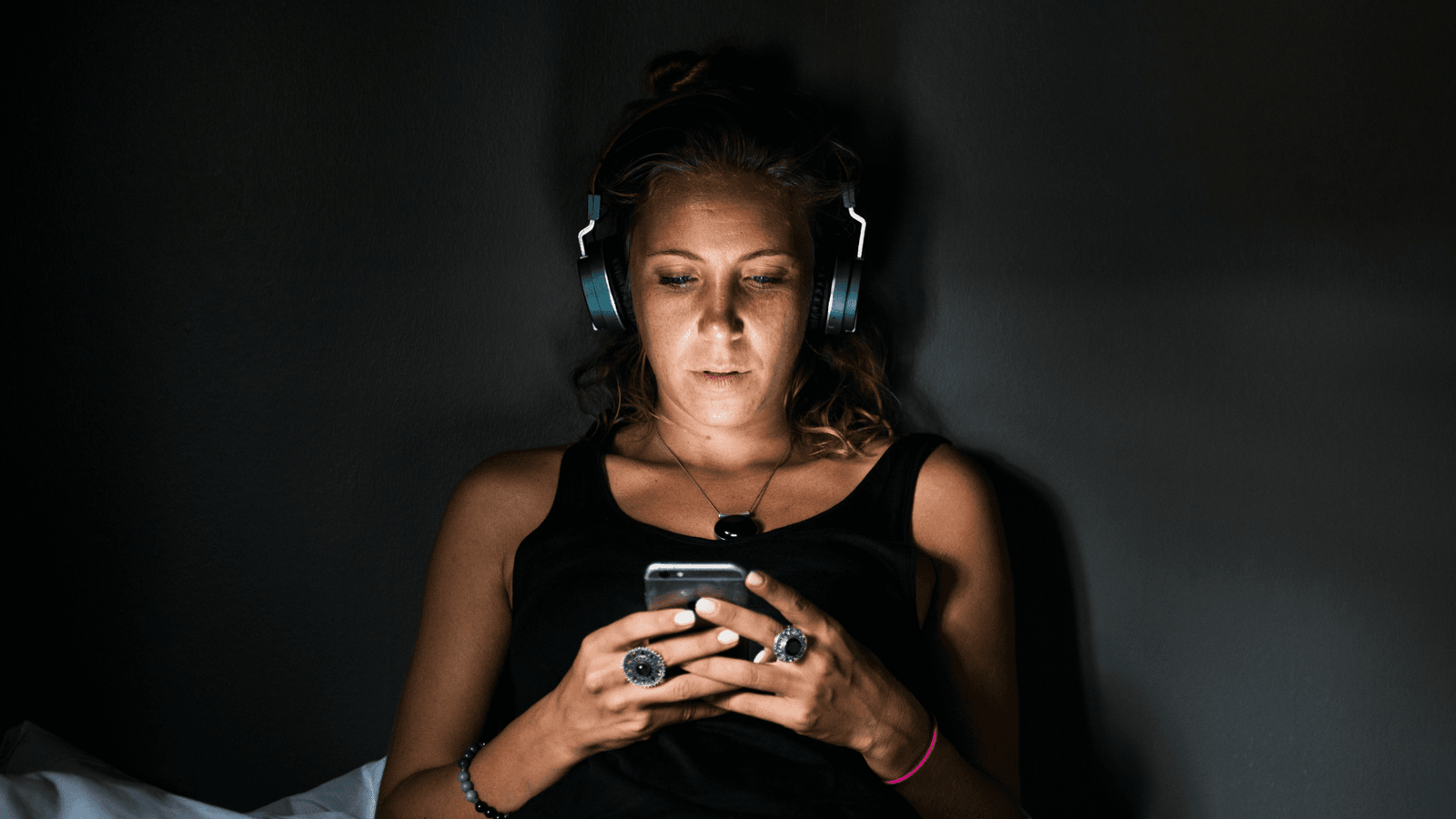 Young woman wearing blue headphones looking at phone