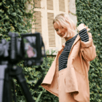 Young woman wearing peached coloured suit recording social media content