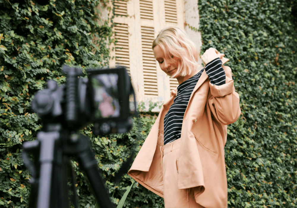 Young woman wearing peached coloured suit recording social media content