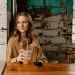 Young woman with long blond hair sitting in coffee shop alone