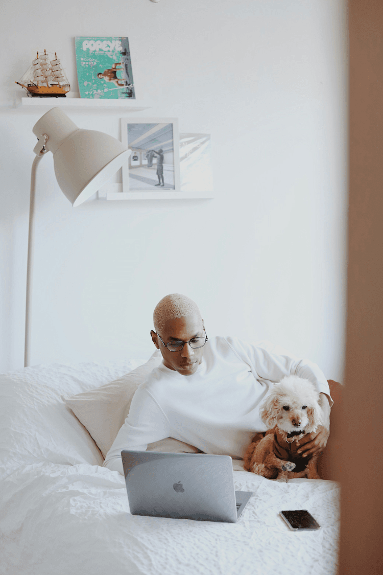 Man Looking at laptop next to cute dog