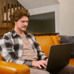Man on orange sofa looking at laptop