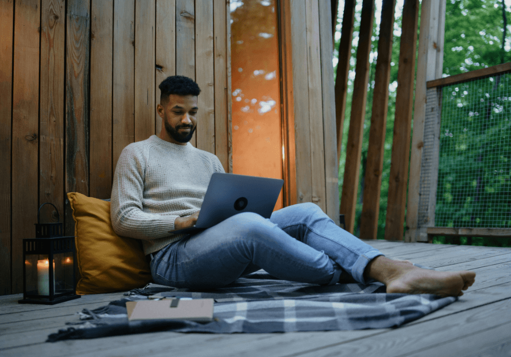 Man sitting on a rug on laptop next to candle