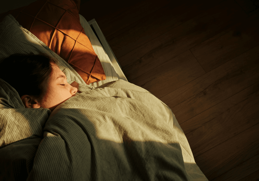 Woman asleep in bed under green duvet