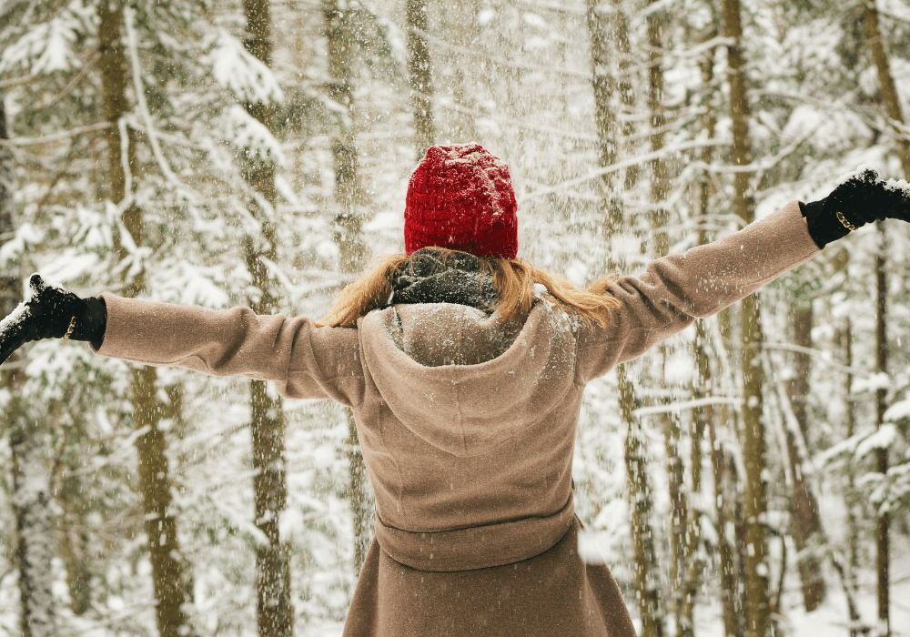 Woman celebrating winter in a snowy forest