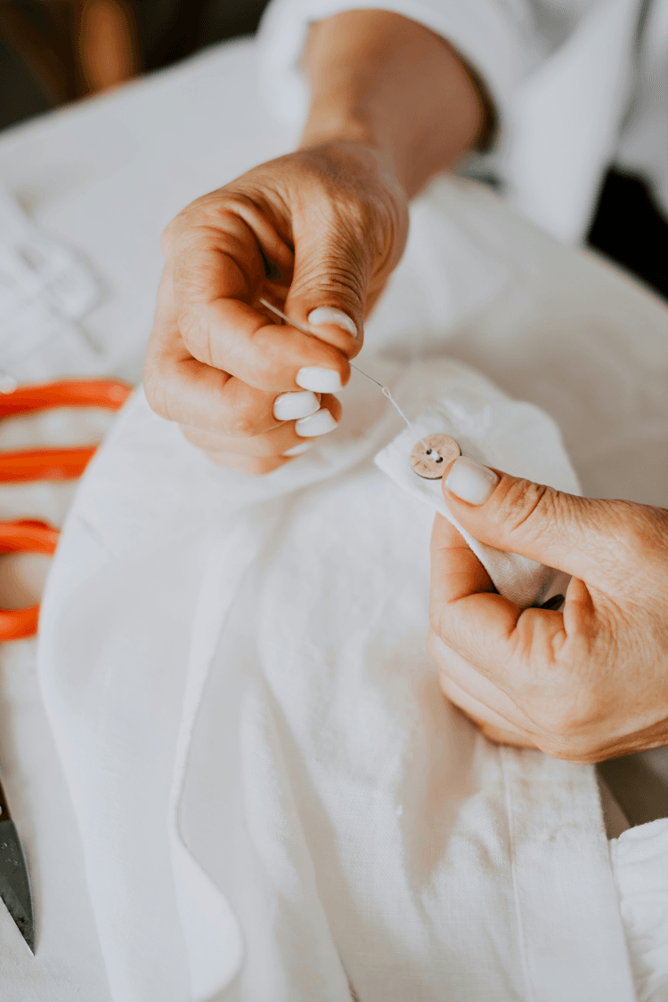 Woman sewing button on to white shirt