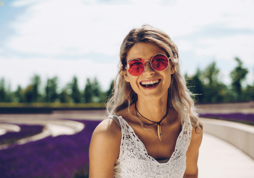 Woman smiling wearing rose tinted glasses representing toxic positivity
