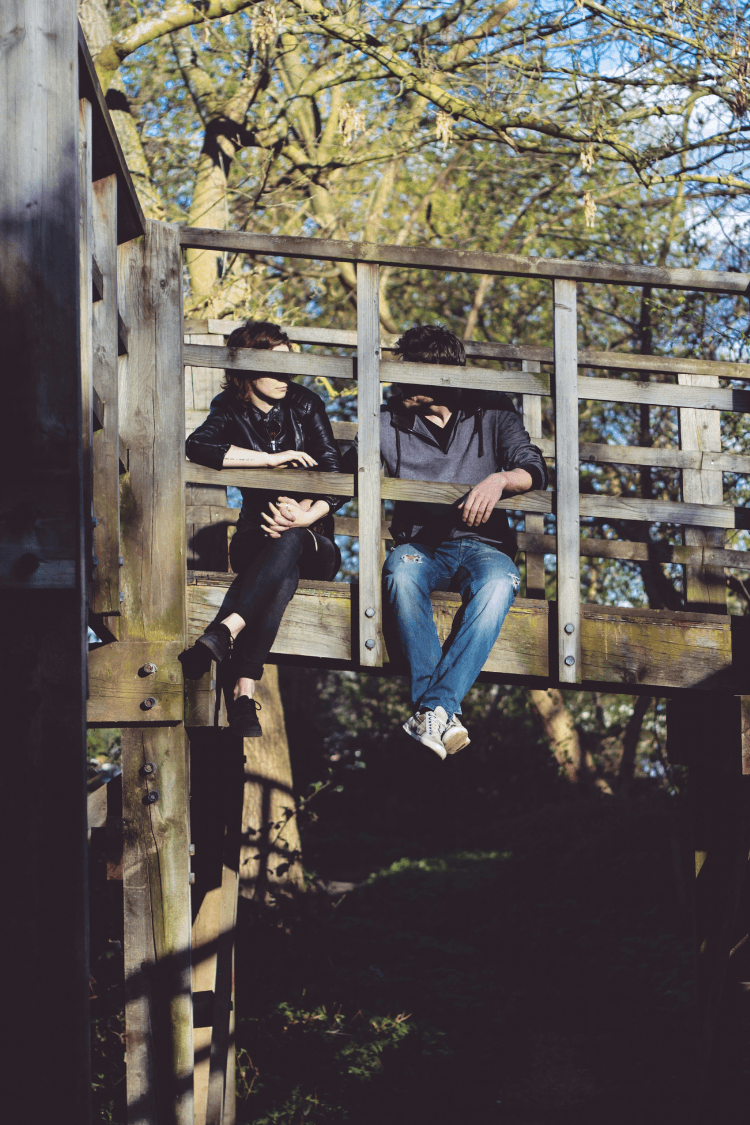 Young couple sitting on wooden bridge talking