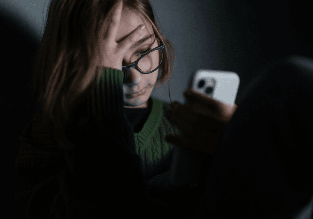 Young girl looking at her smartphone in a darkened room