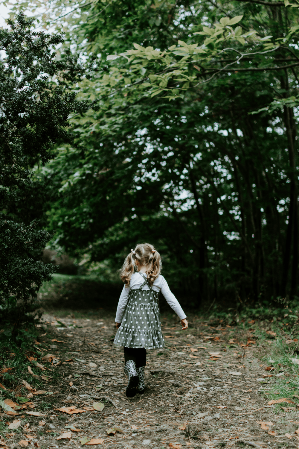 Young girl walking along forest path