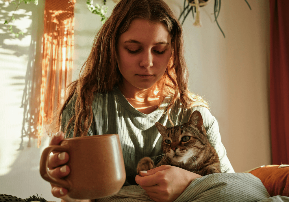 Young woman holding mug and cat