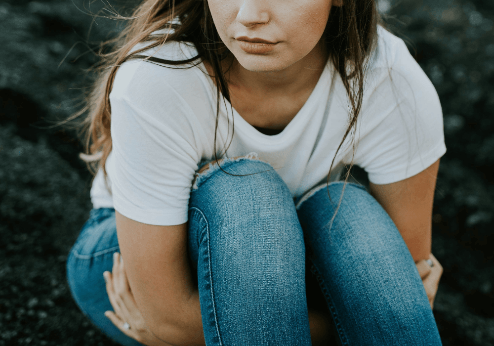 Young woman sitting on ground looking thoughtful