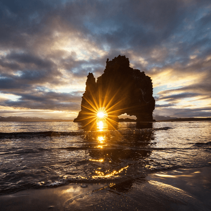 Sun setting behind a rock in the ocean