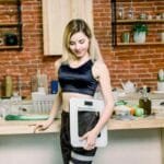 Young woman in gym gear holding bathroom scales