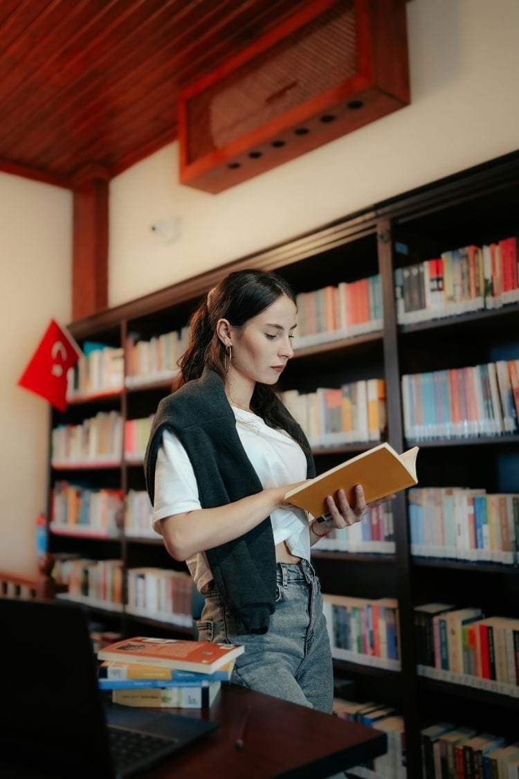 Young woman in library looking at book