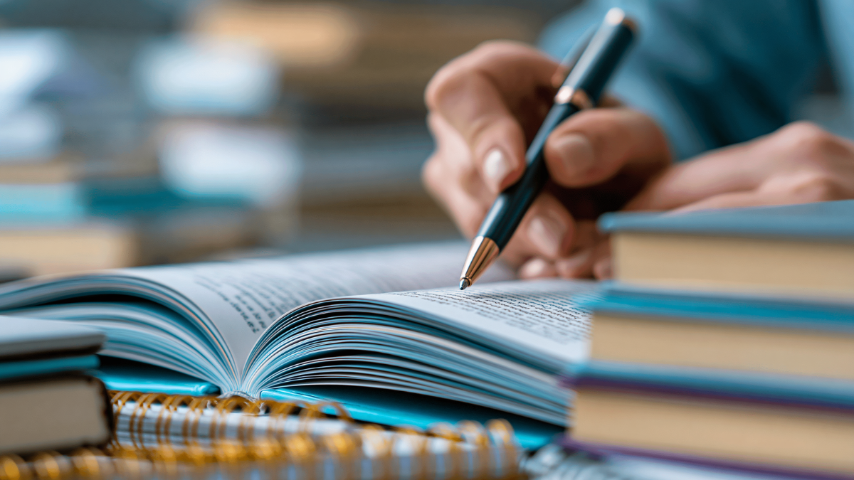 Student holding a pen and writing in a notebook