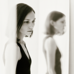Black and white image of a young woman with possible eating disorder looking in a mirror